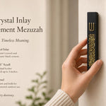 Hand holding a Modern Gold Crystal Inlay Black Cement Mezuzah case with a raised gold Shin and luminous gold crystal and glass inlay, showing the dramatic contrast between the matte black cement body and reflective golden decorative stones