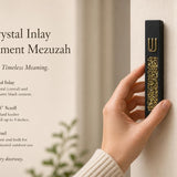 Hand holding a Modern Gold Crystal Inlay Black Cement Mezuzah case with a raised gold Shin and luminous gold crystal and glass inlay, showing the dramatic contrast between the matte black cement body and reflective golden decorative stones