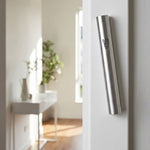 Modern brushed silver aluminum mezuzah mounted on a doorway in a contemporary interior, slim design with understated Shin detail.