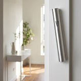 Modern brushed silver aluminum mezuzah mounted on a doorway in a contemporary interior, slim design with understated Shin detail.