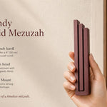 Person holding the Modern Burgundy Pyramid Mezuzah, made of aluminum with a deep red finish, showcasing its architectural stepped design