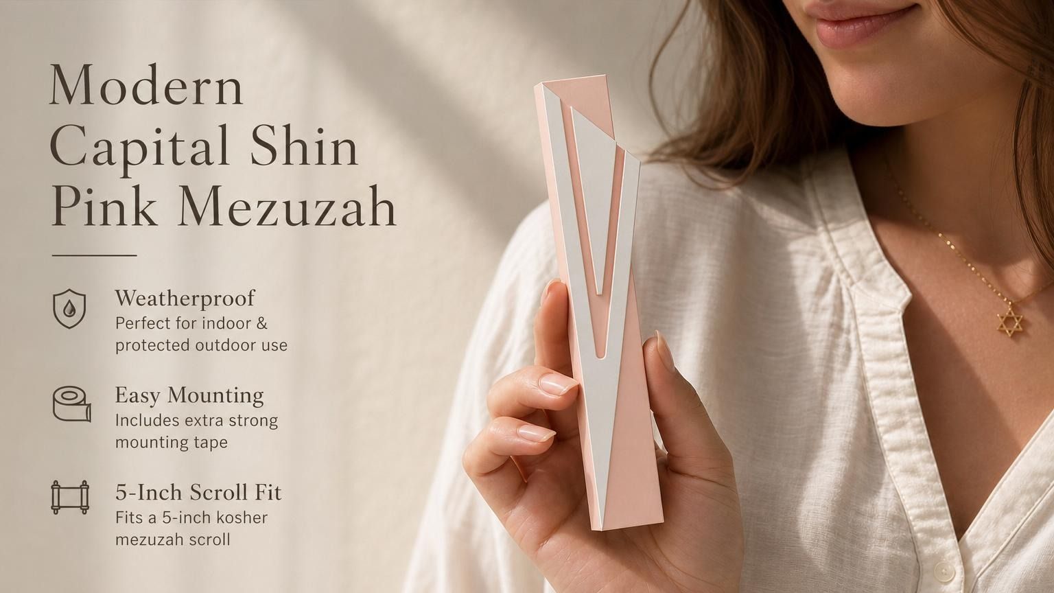 Hand holding a silver and pink aluminum mezuzah case with screw cap, suitable for outdoor doorways, shown in a natural, balanced composition.