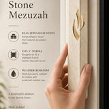 Person holding handcrafted Jerusalem stone mezuzah in a natural indoor setting with editorial style.