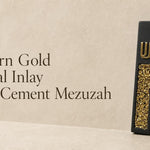 Modern matte black cement mezuzah case featuring a gold crystal and glass inlay with a raised gold Hebrew Shin letter.