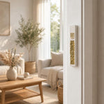 Modern Gold Crystal Inlay White Cement Mezuzah mounted vertically on a light residential doorpost in a bright neutral home, showing the raised gold Shin, slim white cement case, and reflective golden crystal and glass inlay