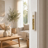 Modern Gold Crystal Inlay White Cement Mezuzah mounted vertically on a light residential doorpost in a bright neutral home, showing the raised gold Shin, slim white cement case, and reflective golden crystal and glass inlay