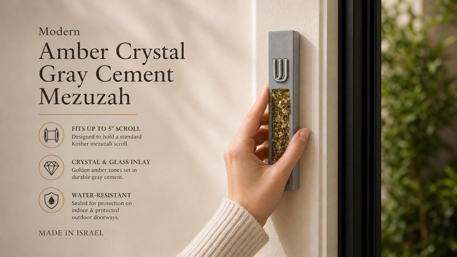 Hand holding a Modern Golden Amber Crystal Inlay Gray Cement Mezuzah case with a raised silver-tone Shin and warm golden amber crystal and glass pieces, showing the contrast between the cool gray cement body and rich honey, bronze, and amber-toned inlay