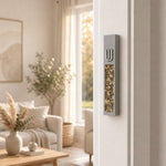Modern Golden Amber Crystal Inlay Gray Cement Mezuzah mounted vertically on a residential doorpost, showing its raised silver-tone Shin, warm amber crystal and glass inlay, and slim gray cement body in a bright neutral home interior