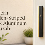 Modern Golden-Striped Black Aluminum mezuzah case mounted on a white doorpost, featuring a sleek matte black rectangular body, narrow vertical gold stripe, and small gold Hebrew Shin. This contemporary black and gold mezuzah case offers a clean minimalist look for modern Jewish homes, front doors, apartments, offices, and interior doorways