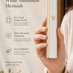 Person holding a white and gold aluminum mezuzah showing its sleek design with natural light and generous space.