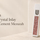 unique modern white cement mezuzah with a raised silver-tone Shin and a vertical panel of pink, rose, blush, and translucent crystal and glass inlay, styled against a soft neutral backdrop