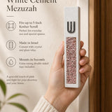 Hand holding a Modern Pink Crystal Inlay White Cement Mezuzah case with a raised silver-tone Shin and sparkling pink, blush, rose, and translucent crystal and glass pieces set into the slim white cement body