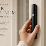 Hand-held view of the modern waterproof black aluminum outdoor mezuzah, showcasing its slim black silhouette with a raised silver Shin