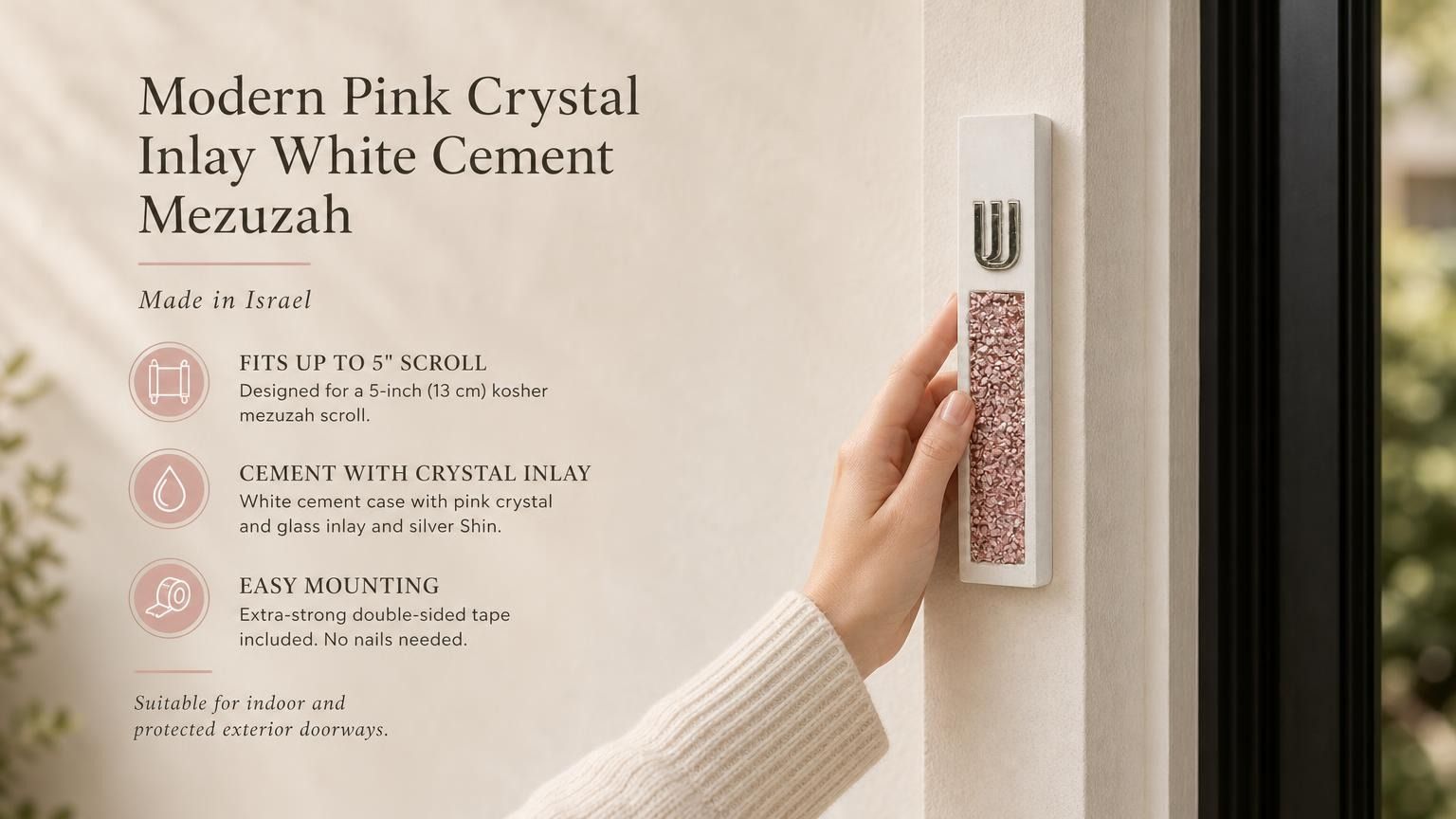 Handheld modern white cement mezuzah case featuring a raised silver-tone Shin and pink crystal and glass inlay, shown beside product information in a warm neutral home setting to highlight its slim profile, soft rose color palette, and contemporary styling