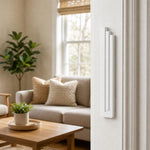 Indoor lifestyle scene showing the modern white pyramid mezuzah mounted on a residential doorpost, with a view into the room.