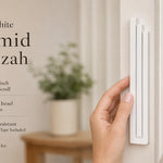 Person holding the exact modern white pyramid mezuzah showcasing its stepped architectural design, on the left with editorial text on the right in neutral tones