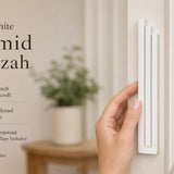 Person holding the exact modern white pyramid mezuzah showcasing its stepped architectural design, on the left with editorial text on the right in neutral tones