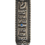 Petite Moroccan style pewter Mezuzah with Hebrew blessing, suitable for home doorways, featuring intricate details and placed on a white studio surface.