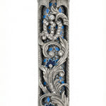 Blue accented Moroccan garden mezuzah with floral and vine motifs, layered detail, and hope rays, designed for home blessing and adornment.