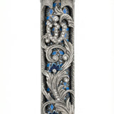 Blue accented Moroccan garden mezuzah with floral and vine motifs, layered detail, and hope rays, designed for home blessing and adornment.
