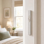 Eternal Flame silver aluminum mezuzah mounted on a white bedroom doorpost, with a minimalist raised ner tamid and Shin design in a bright contemporary Jewish home