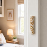 Natural Jerusalem stone mezuzah with golden olive branch mounted on a residential doorpost in an indoor setting