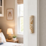 Natural Jerusalem stone mezuzah with golden olive branch mounted on a residential doorpost in an indoor setting