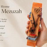 Hand holds the vibrant orange violin-themed mezuzah with detailed ceramic texture, showcasing its musical motif perfect for music lovers.