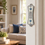 Pearlescent white pewter mezuzah case mounted on an interior doorpost with silver Shin and blue heart-shaped Stars of David