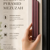 Person naturally holding the exact source mezuzah at realistic scale, with editorial text space, highlighting its shape, color, and material in a premium layout.