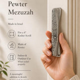 Person holding an exact Jerusalem pewter mezuzah case at realistic size, highlighting traditional design and material.