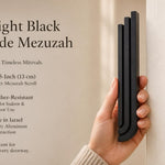 Person naturally holding the Midnight Black Cascade Mezuzah with editorial space for product showcase.