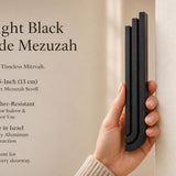 Person naturally holding the Midnight Black Cascade Mezuzah with editorial space for product showcase.