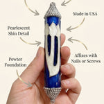 Person supporting a Heavenly Blue mezuzah, emphasizing its elegant design, material, and craftsmanship in a clean, minimalist style.