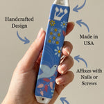 Person supporting a Dove of Peace ceramic mezuzah, showcasing material and size details in a clean setting.