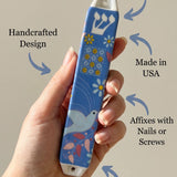 Person supporting a Dove of Peace ceramic mezuzah, showcasing material and size details in a clean setting.