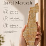 Person holding the Eretz Yisrael cream Jerusalem stone mezuzah, showing its width and gold detail.