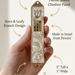 Hand supporting an elegant Pearl enamel mezuzah case with gold trim and dove motif, showcasing its peaceful design and Hebrew details.