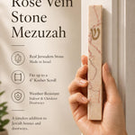Person naturally holding a Jerusalem stone mezuzah in hand, highlighting the textured natural material and Hebrew detail, in a premium product presentation.