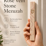 Person naturally holding a Jerusalem stone mezuzah in hand, highlighting the textured natural material and Hebrew detail, in a premium product presentation.
