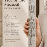 Hand holding the gray Etz Chaim Jerusalem stone mezuzah showing size and carved detail.