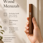 Close-up of a hand holding the 6.5-inch mahogany wood mezuzah showing grain and finish.