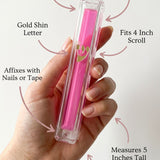 Person holding a clear pink Lucite Mezuzah display emphasizing its material, size, and mounting features for home placement.
