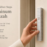 Person holding the exact Modern Silver Steps Aluminum Mezuzah at natural scale, with editorial text and negative space for in-store display.