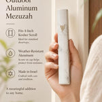Person holding sleek white marble-inspired outdoor aluminum mezuzah with Hebrew Shin and gold accents.