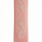 Pink glass mezuzah decorated with adorable baby feet design, displayed on a white background with soft reflection for an elegant look.