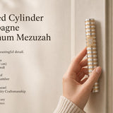 Person holding the exact Grooved Cylinder Champagne Aluminum Mezuzah in a natural pose, showcasing its sculptural profile and design details.