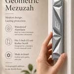 Hand holding Cyber Prism Silver Geometric Mezuzah on one side, with editorial text on the other, in a warm natural light setting.