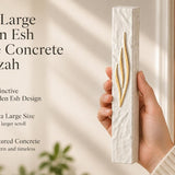 Hand holding an extra large golden Esh mezuzah made of textured white concrete for a doorway.