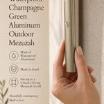 Close-up of a person holding the champagne green aluminum outdoor mezuzah, emphasizing its sleek and muted metallic finish.